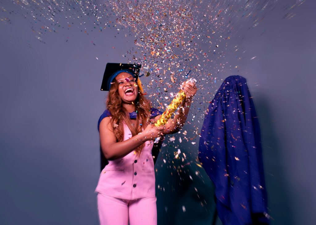 A woman in graduation attire celebrating with confetti in Minna, Nigeria.