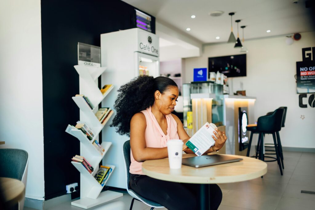 Learning Tech in Lagos: What Nobody Tells Beginners 
Black woman reading a book in a modern Lagos cafe, relaxed and focused atmosphere.