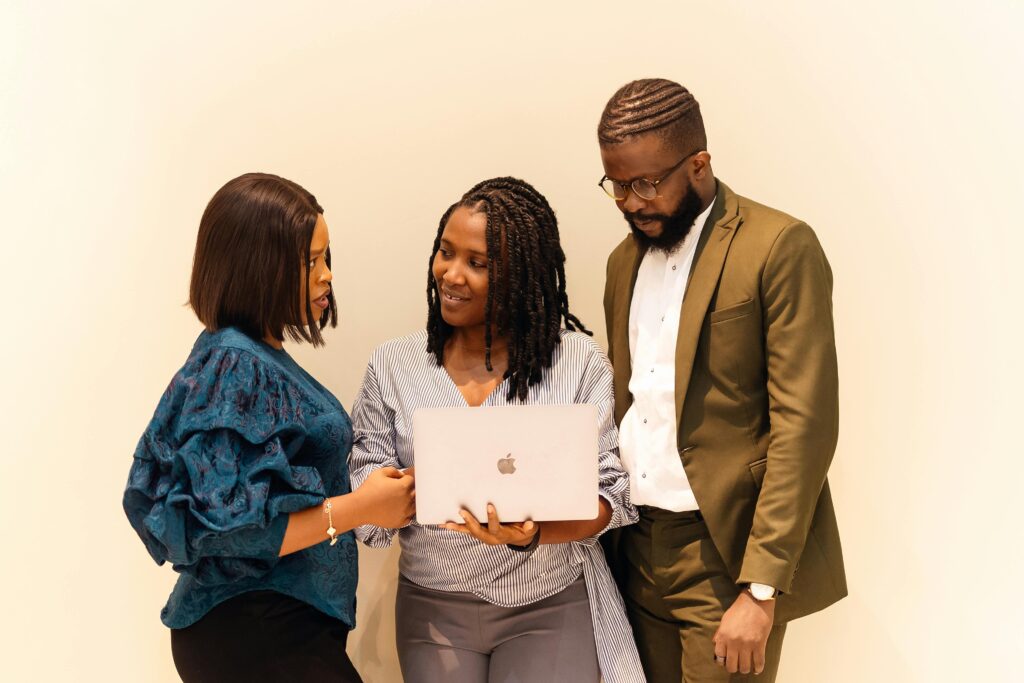 Three professionals engaged in collaborative work with a laptop in an office setting.