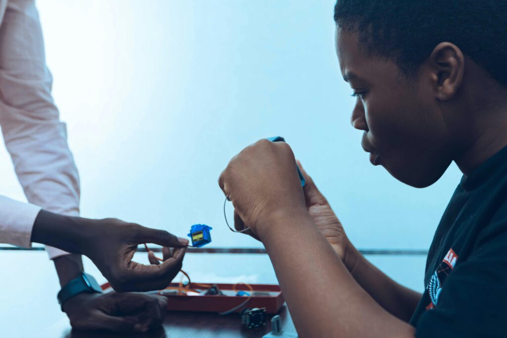 Two students work on a hands-on project, connecting components in a tech class.